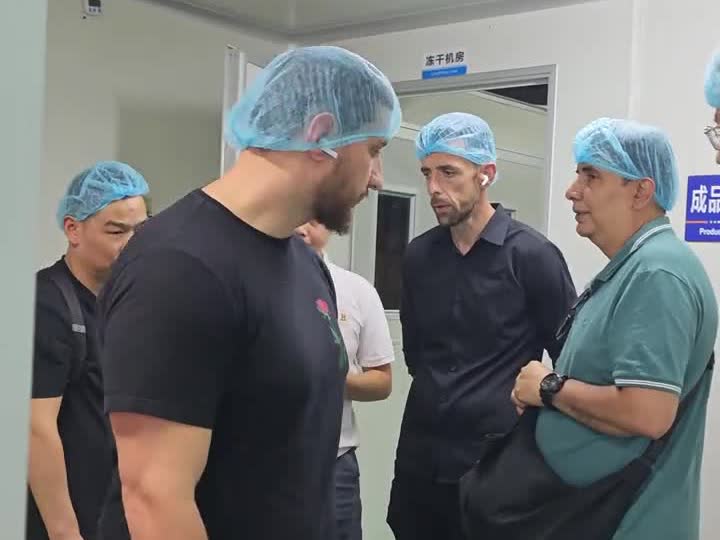 Asian Tide factory staff discussing peptide production equipment in a cleanroom